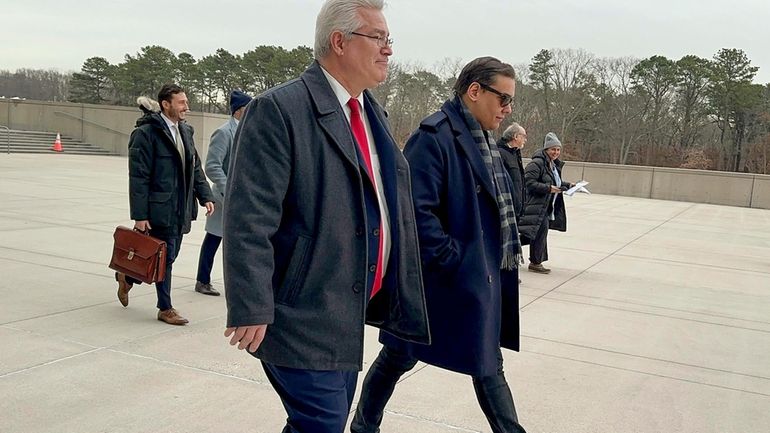 Former U.S. Rep. George Santos, right, leaves federal court with...