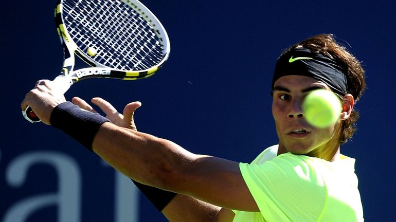 Rafael Nadal of Spain returns a shot to Gilles Simon...