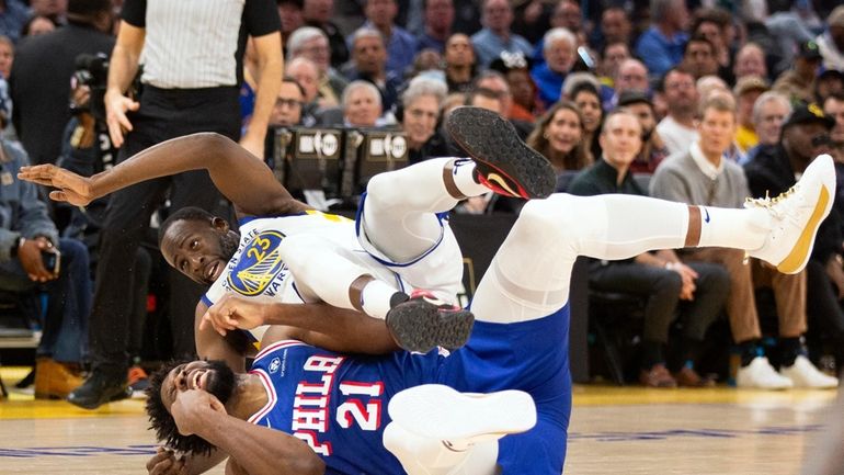 Golden State Warriors forward Draymond Green (23) falls over Philadelphia...