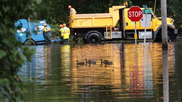 A work crew stands in floodwaters on Mills Pond Road...