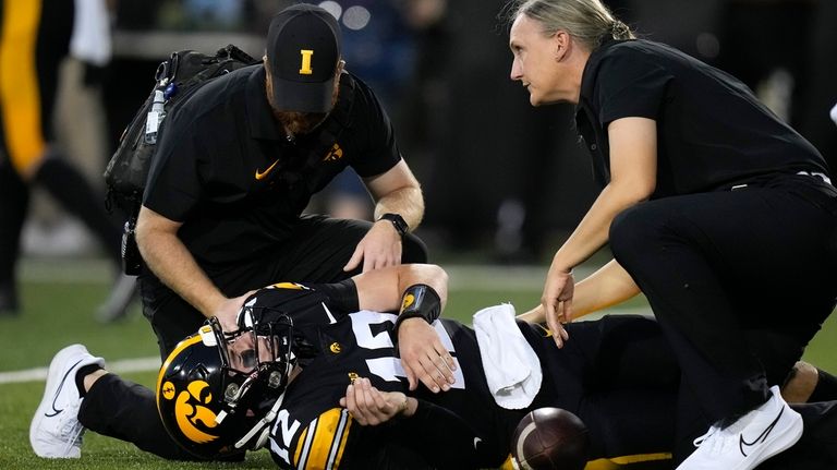 Iowa quarterback Cade McNamara (12) lies injured on the field...