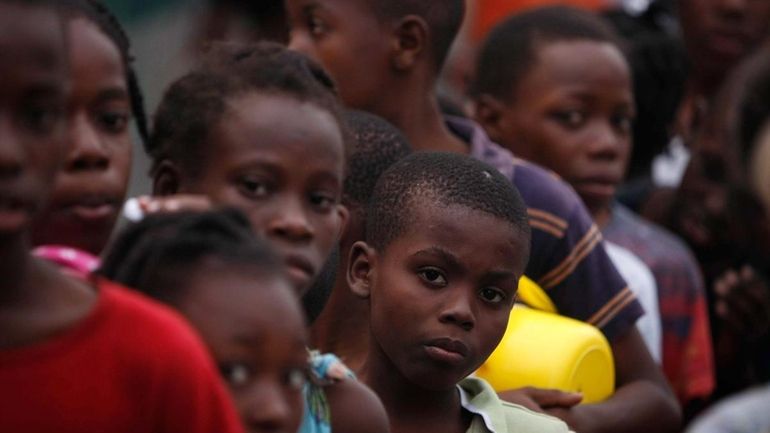 Children line up to receive food in front of the...