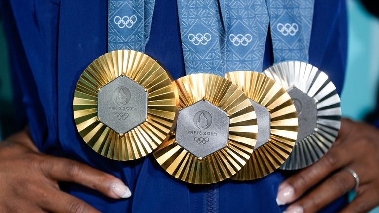 Simone Biles, of the United States, holds up her medals...