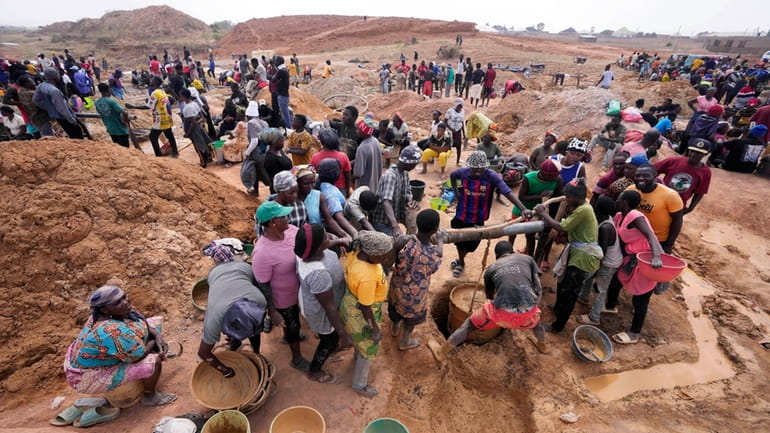 Miners work at an illegal tin mining site in Jos,...