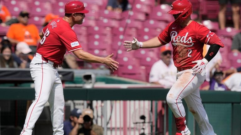 Cincinnati Reds' Ty France, right, celebrates with third base coach...