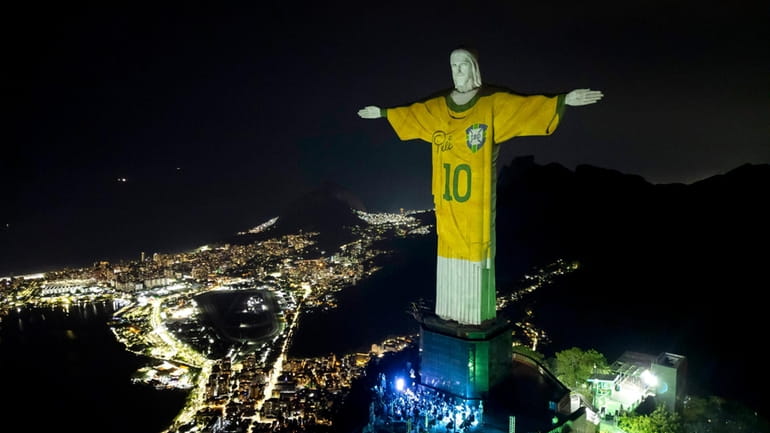 The Christ the Redeemer statue is illuminated with an image...