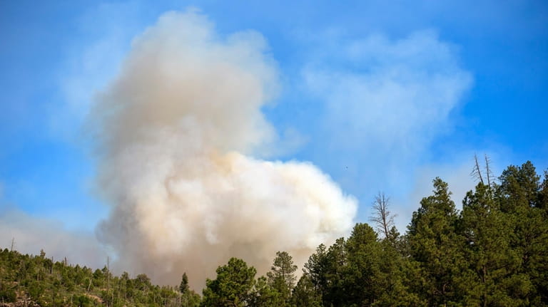 Smoke from a wildfire rises over the mountains of Ruidoso,...