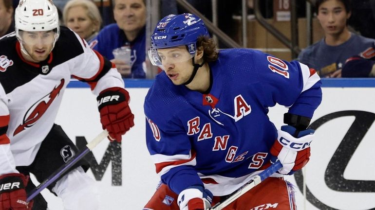 Artemi Panarin #10 of the Rangers plays the puck against Michael...