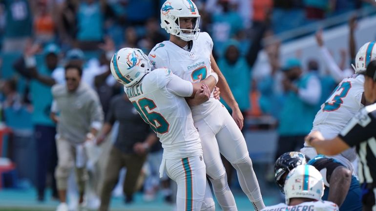 Miami Dolphins punter Jake Bailey (16) lifts place kicker Jason...