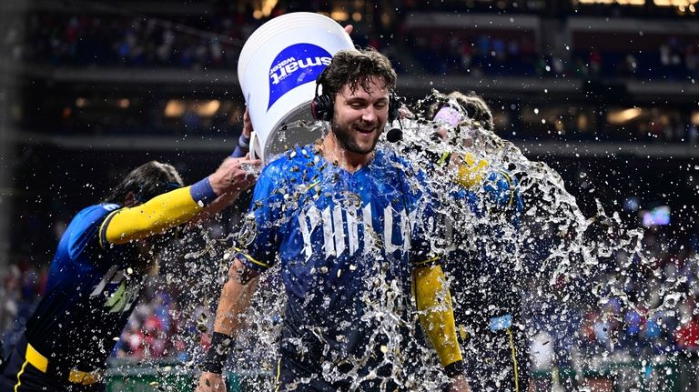 Philadelphia Phillies' Trea Turner, center, is doused by Brandon Marsh,...