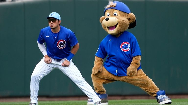 FILE. The Chicago Cubs mascot playfully stretches with Seiya Suzuki...