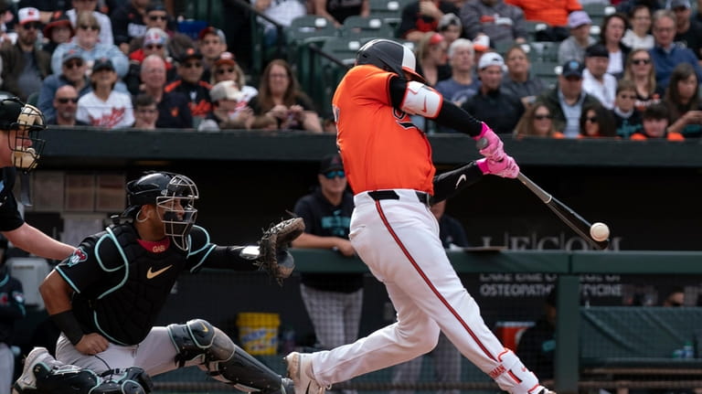 Baltimore Orioles catcher Adley Rutschman, right, hits during a baseball...