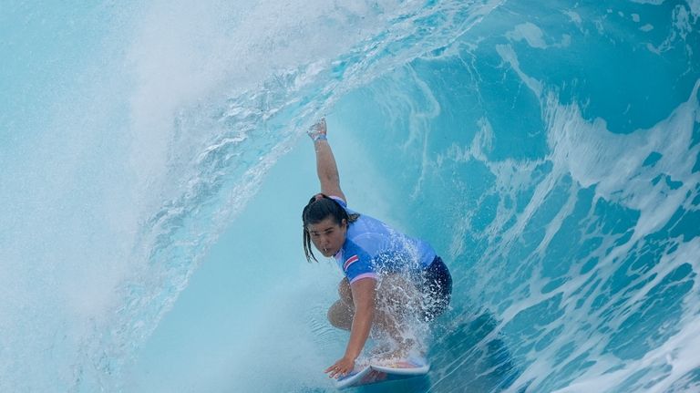 Brisa Hennessy, of Costa Rica, surfs during the first round...