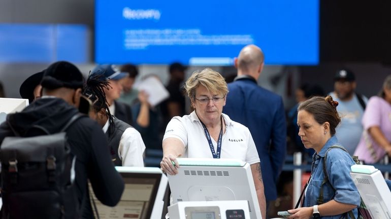 A Delta Air Lines employee helps a traveler at Kennedy...