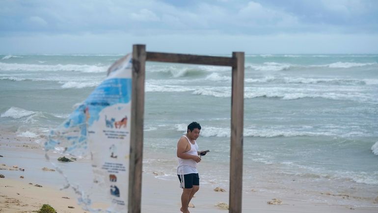 A man walks on the beach in the aftermath of...