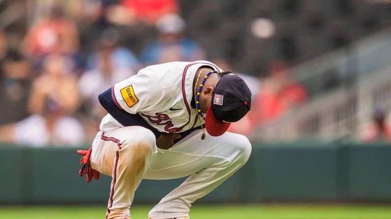 Atlanta Braves' Ozzie Albies holds his wrist after an injury...