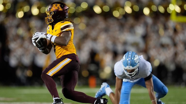 Minnesota defensive back Justin Walley, left, runs with the football...