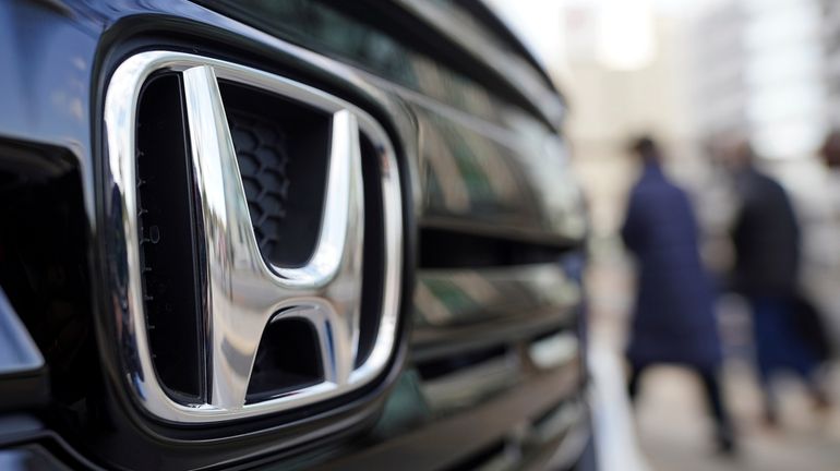 People walk near the logo of Honda Motor Company at...