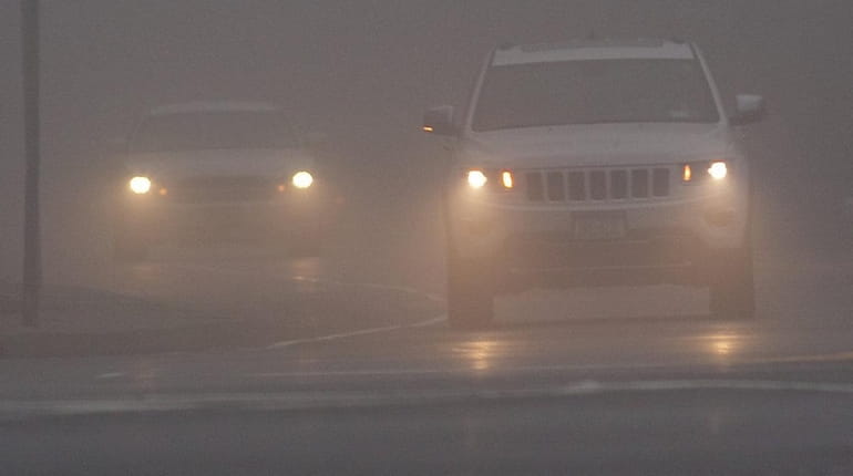 Cars drive in the fog Wednesday morning, Dec. 23, 2015,...