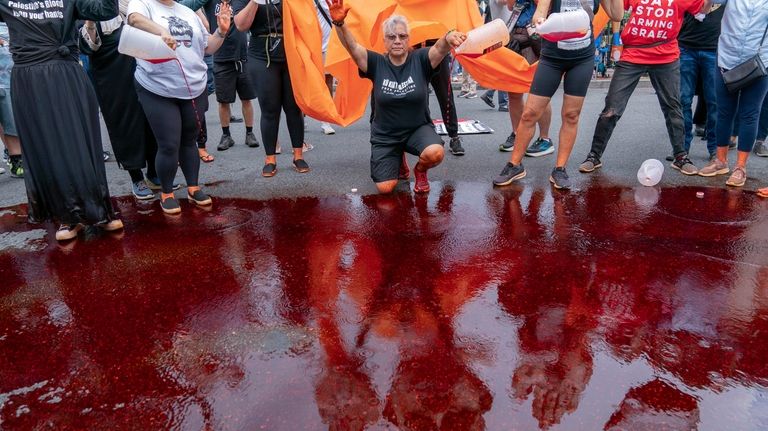 Demonstrators pour red liquid on the asphalt as they protest...