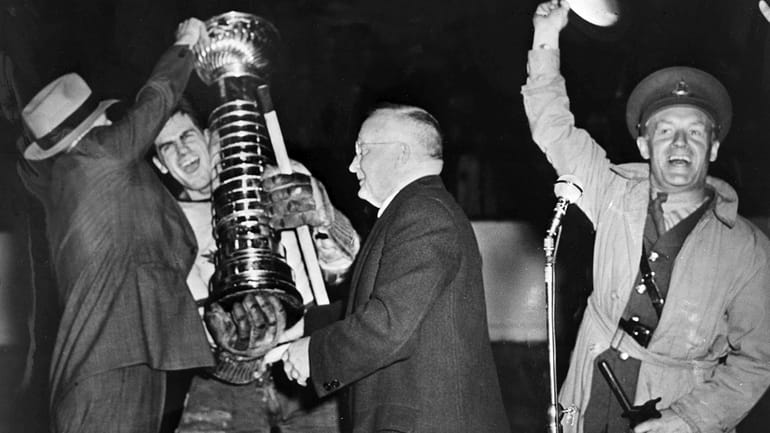 NHL President Frank Calder, center, presents the Stanley Cup to...
