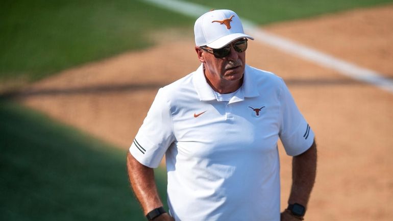 Texas head coach Mike White watches from third base during...