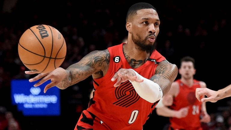 Portland Trail Blazers guard Damian Lillard, left, passes the ball...