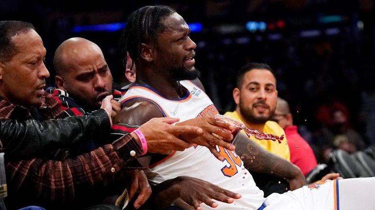 Knicks forward Julius Randle falls into the crowd after shooting...