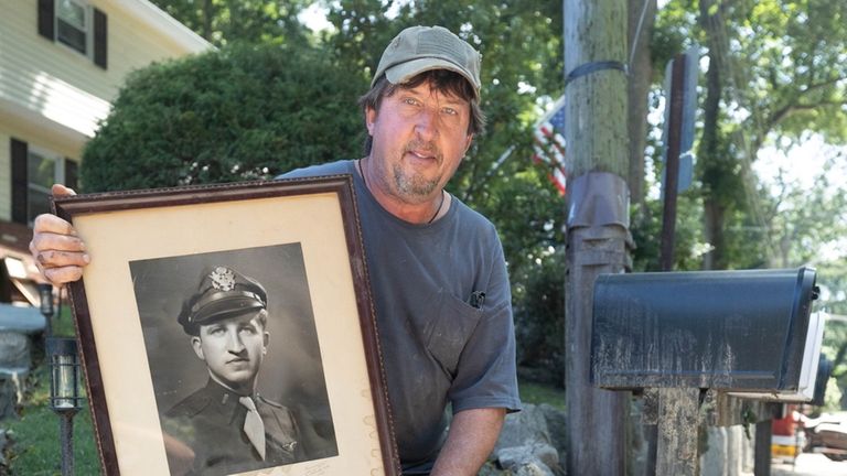 Jeff Litzko holds a damaged painting of his father after a flood that devastated...