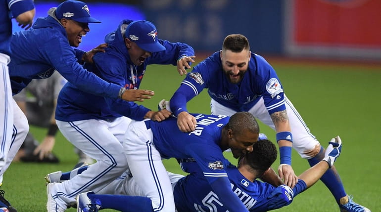 Toronto Blue Jays players mob Russell Martin (bottom) after he...