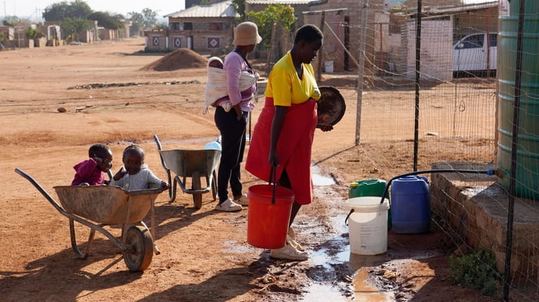 Residents gather at a water tank to collect water in...