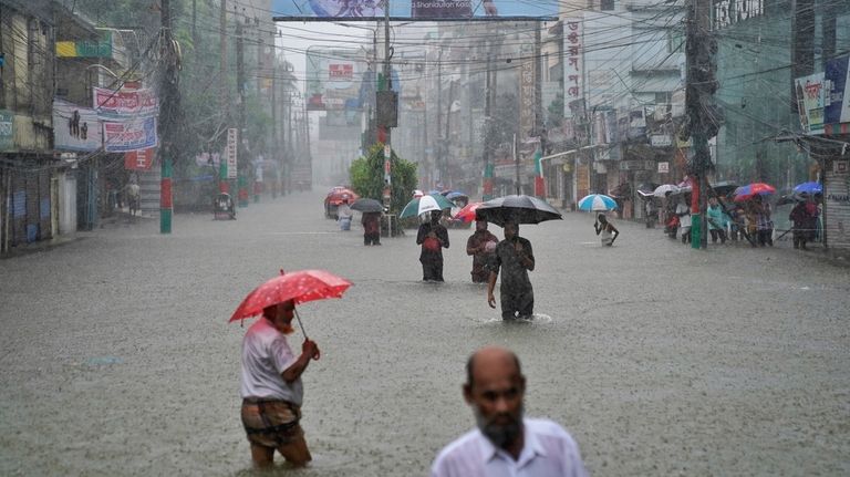 People navigate a flooded street following incessant rains in Feni,...