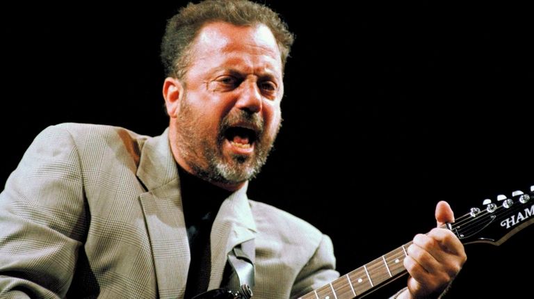 Joel belts out a tune while playing guitar at The Garden...