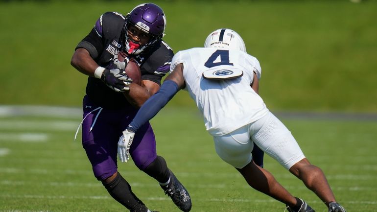 Northwestern running back Cam Porter, left, is tackled by Penn...