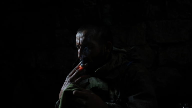 A Ukrainian serviceman smokes a cigarette while taking a cover...