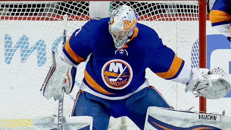 Islanders goaltender Thomas Greiss swipes the puck aside after a...