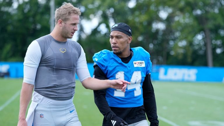 Detroit Lions quarterback Jared Goff, left, walks off the field...