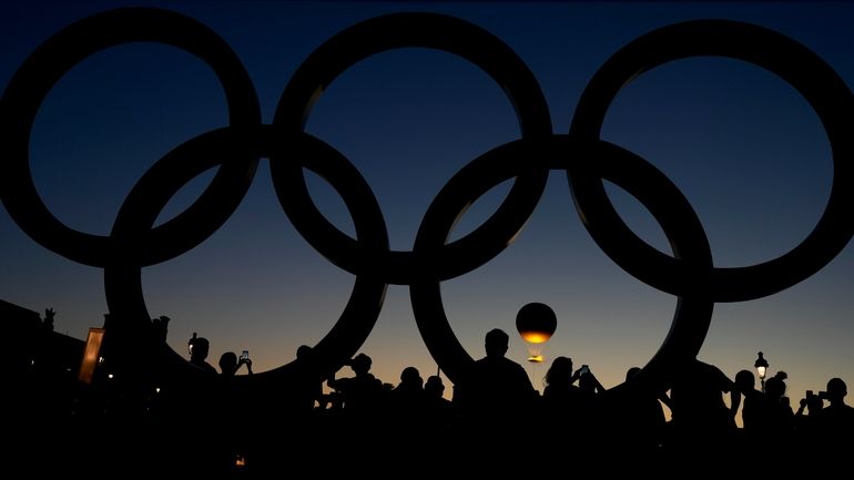 People watch the cauldron rise at sunset by the Olympic...