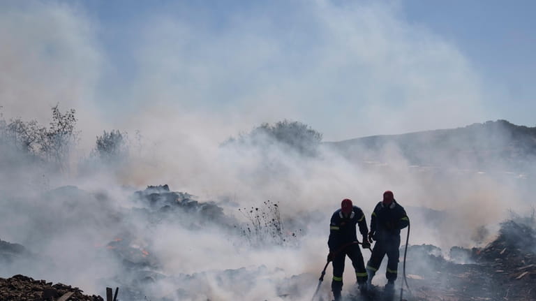 Firefighters try to extinguish the fire burning in Koropi suburb,...