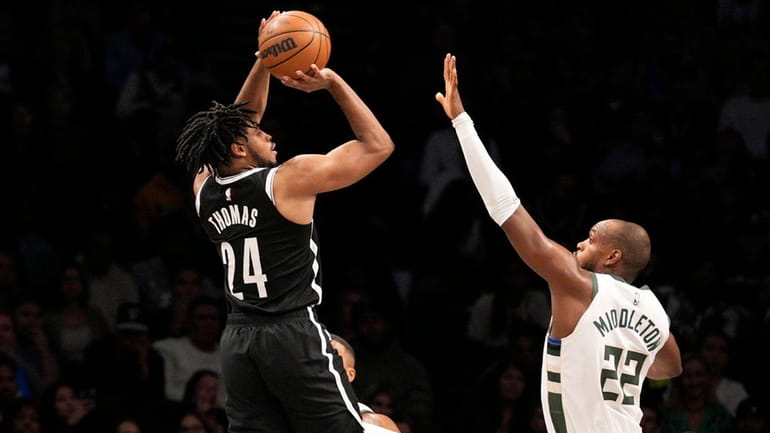 Cam Thomas of the Nets shoots over Khris Middleton of...