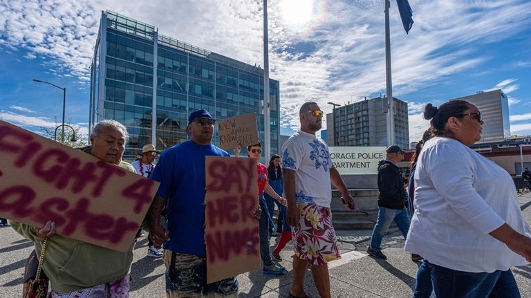 Attendees walk past the police headquarters during a march for...