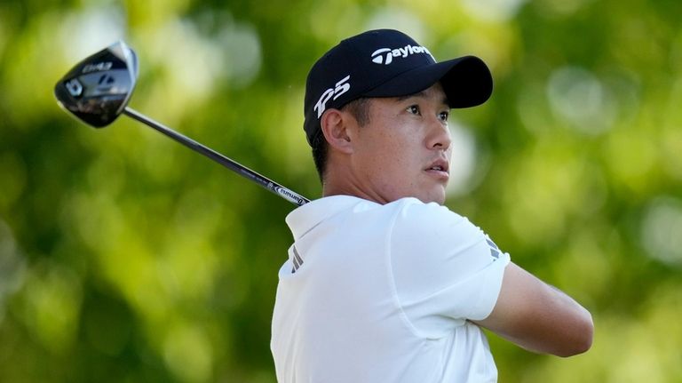 Collin Morikawa watches his tee shot on the 18th hole...