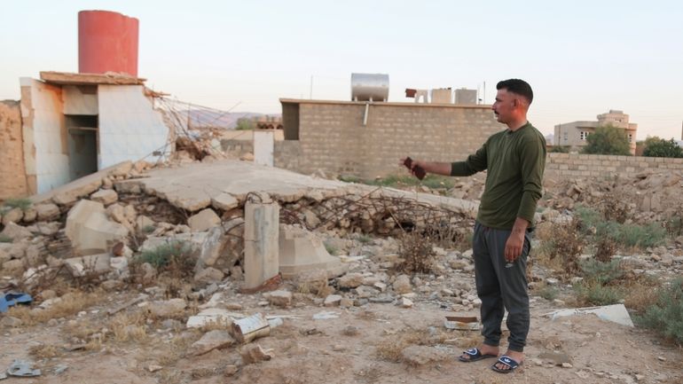 Hadi Shammo, 30, a Yazidi returnee, stands amid the wreckage...