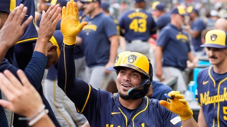 Milwaukee Brewers' Willy Adames reacts in the dugout after hitting...