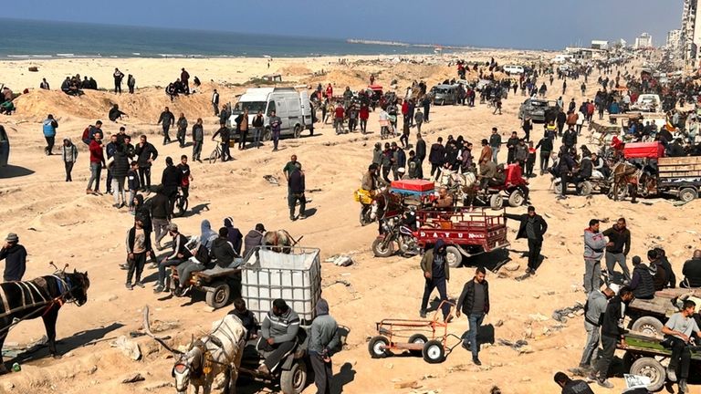 Palestinians wait for humanitarian aid on a beachfront in Gaza...