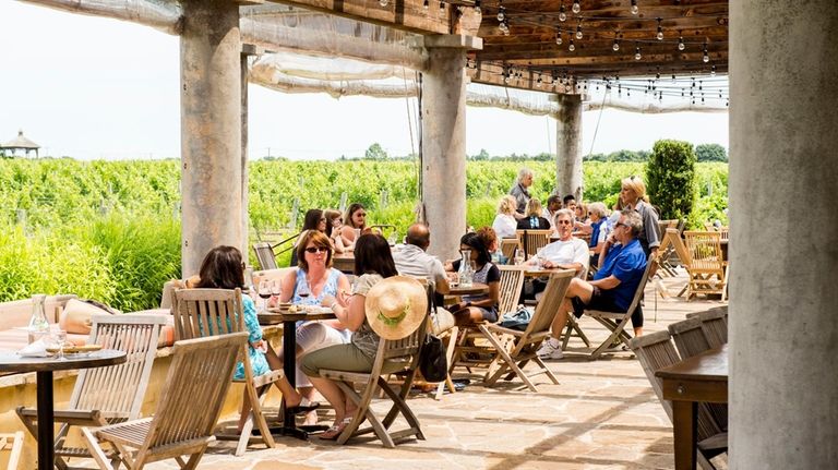 People sit on the outside patio next to the vineyard...