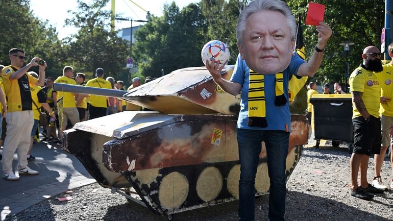 A dummy tank stands next to an activist wearing a...