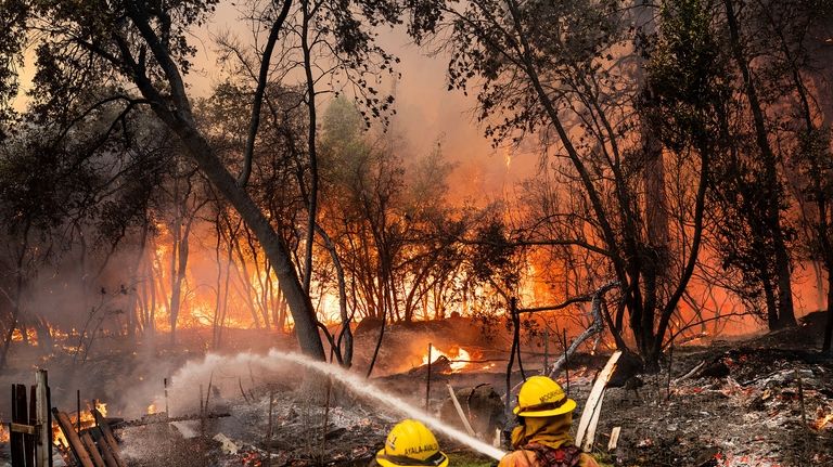 Firefighters spray water while battling the Park Fire in the...