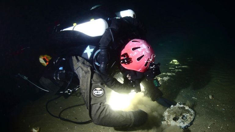 Discovery team member Joe Mazraani fans away the sand to...