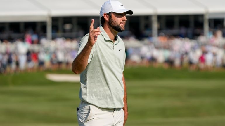 Scottie Scheffler waves after making a putt on the 18th...